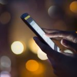 Woman using her mobile phone , city skyline night light backgro